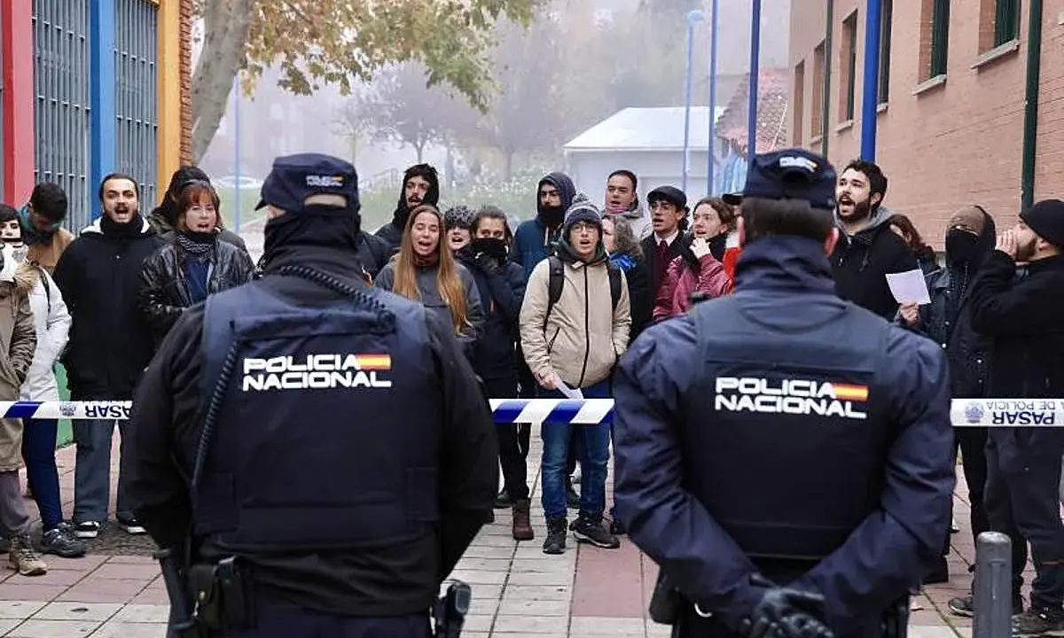 Policía Nacional vigila a un grupo de manifestantes que protestan contra un desahucio.
