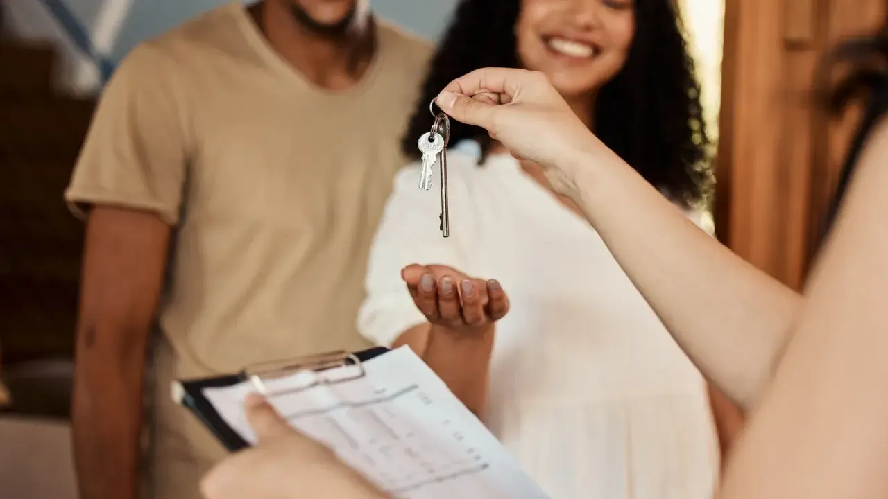 Pareja feliz recibe llaves de su nuevo hogar. Se discute la duración del contrato de alquiler.