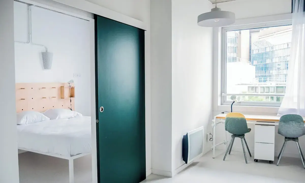 Habitación moderna con cama y escritorio. La puerta corredera verde es un detalle llamativo en este espacio, como un ecla noisy le grand.