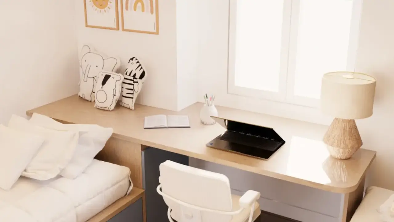 Un escritorio de madera con un portátil, libro y lámpara, junto a una cama y cojines de animales. Este es un ejemplo de cómo un **loft que es** funcional y acogedor.