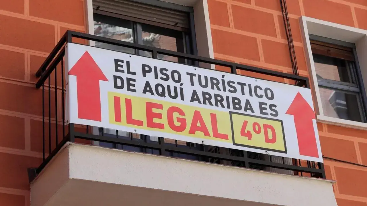 Cartel en balcón: "El piso turístico de aquí arriba es ilegal". Prohibición pisos turísticos.