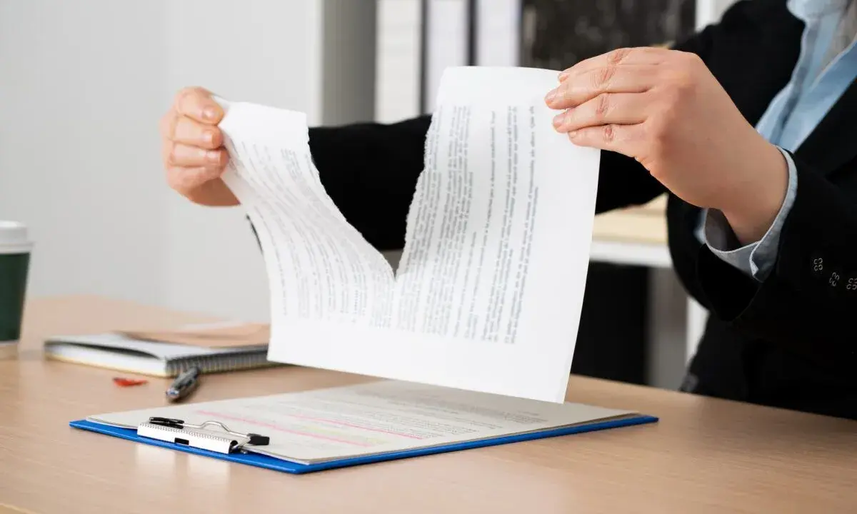 Manos rasgando un contrato, simbolizando la indemnización por incumplimiento de contrato de alquiler.
