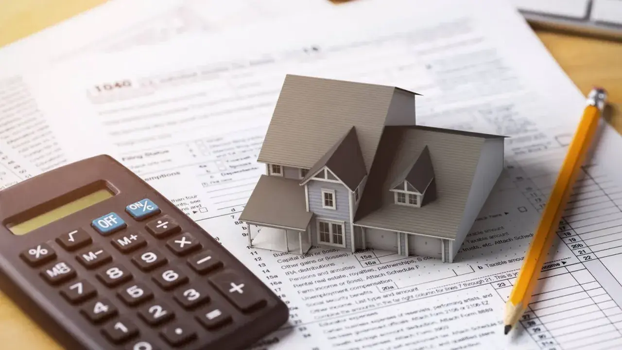Casa modelo sobre formulario 1040, calculadora y lápiz. El arte 3 lau se relaciona con la planificación fiscal.