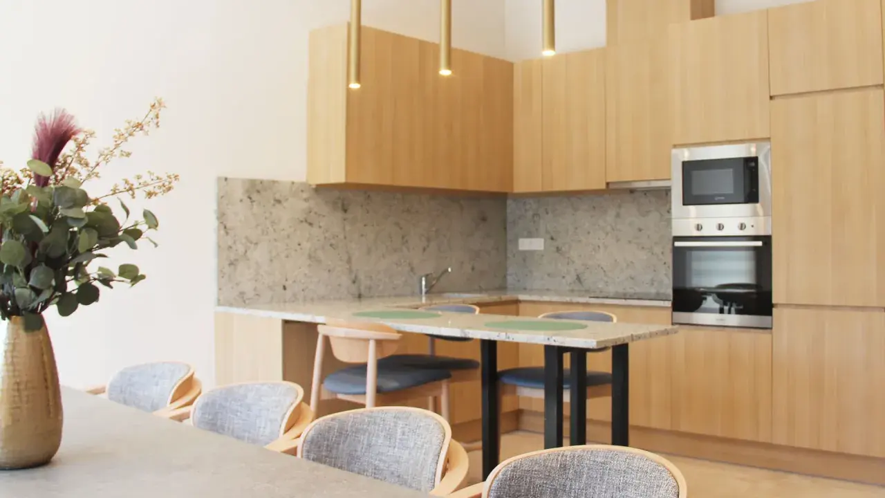 Estudio moderno en Livensa Living Studios Málaga Feria, con cocina equipada, encimera de granito y comedor con sillas cómodas.
