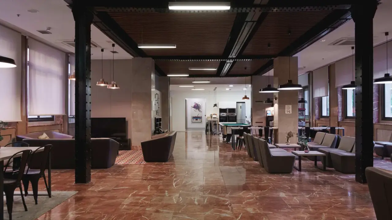 Amplio salón con suelo de mármol rojo, sofás, mesas y una mesa de billar. La **residencia diagonal** ofrece un espacio moderno y acogedor.