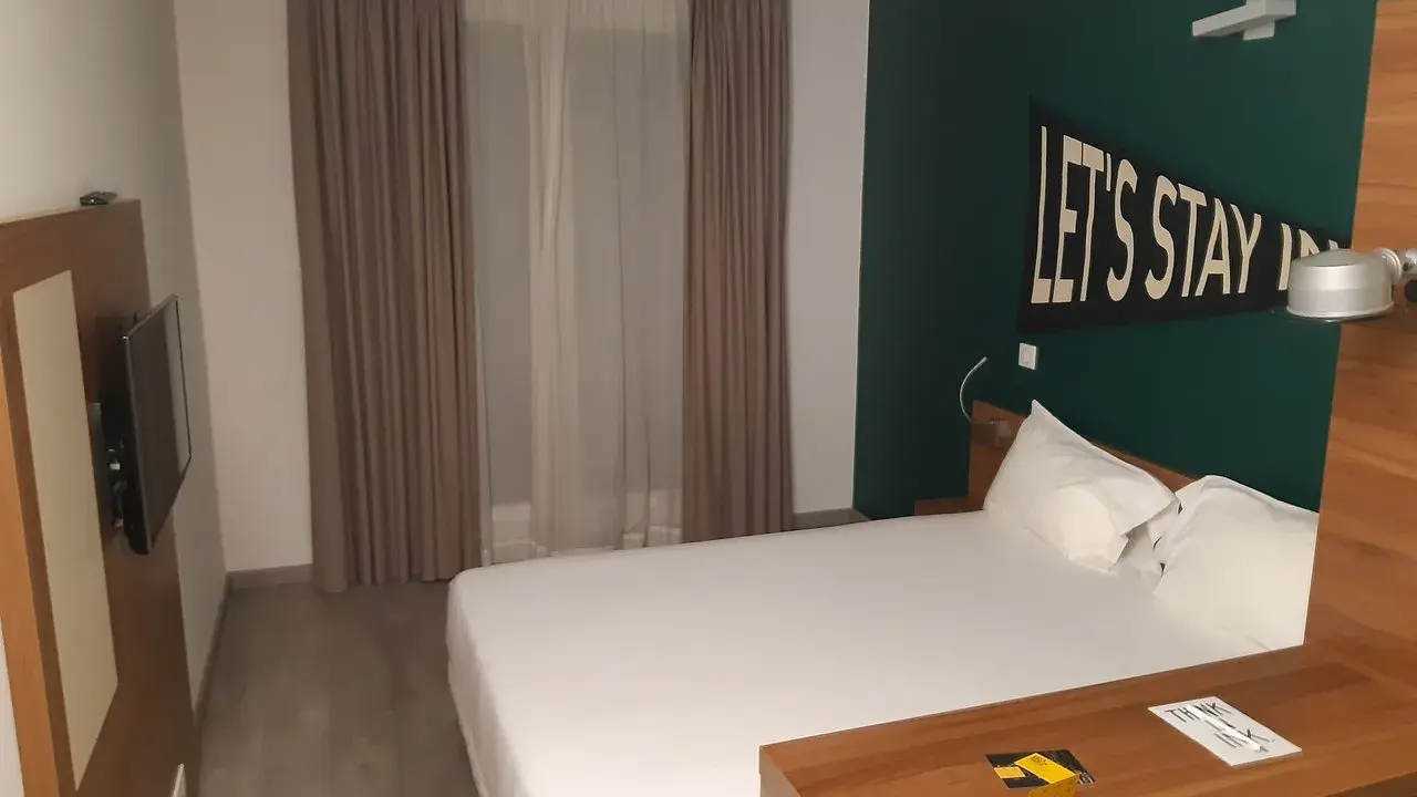 Habitación moderna en The Student Hotel Paris. Cama blanca, escritorio de madera y decoración "Let's Stay In".