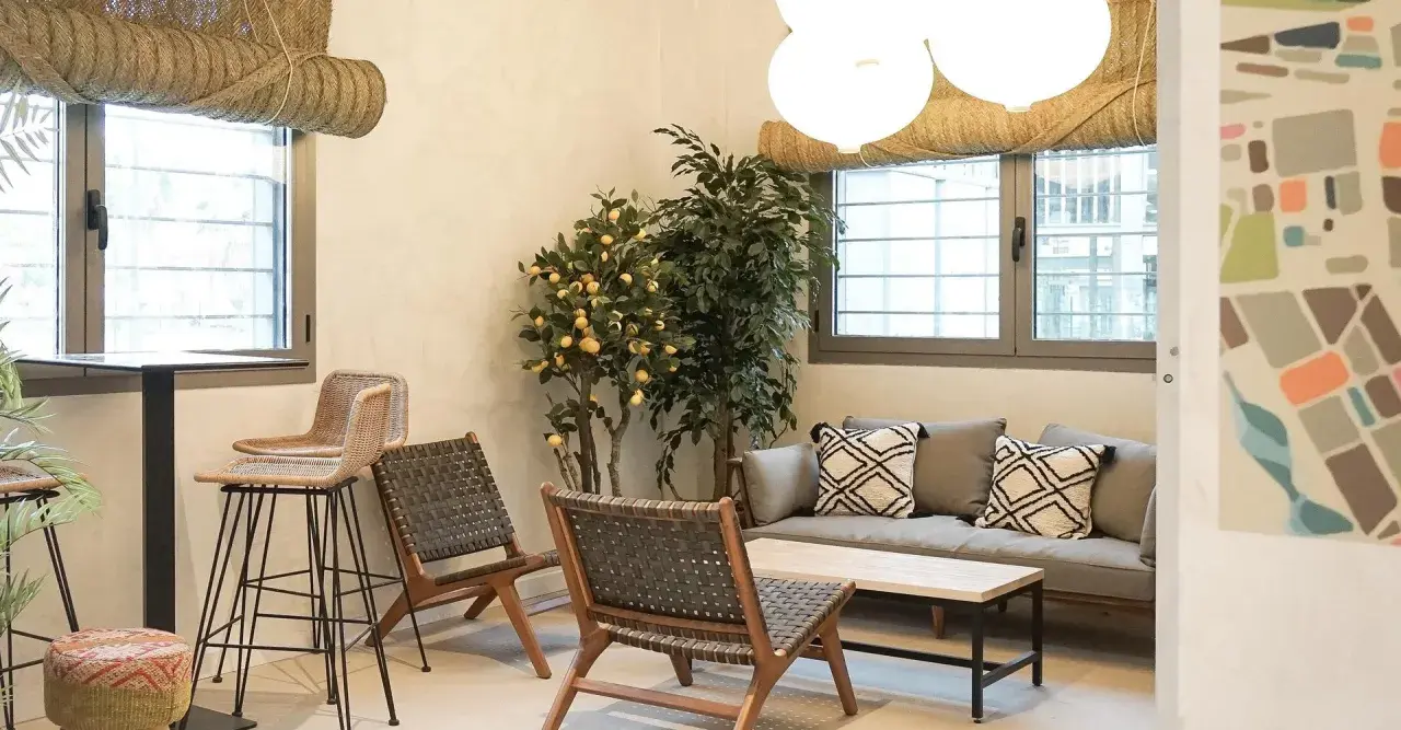 Un espacio acogedor con sofá, sillones de mimbre y un limonero, ideal para relajarse en los lumiere apartamentos.