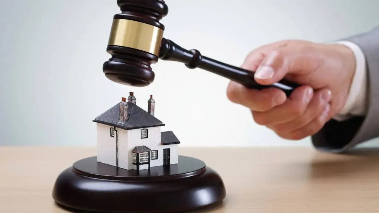 Martillo de juez golpea una casa en miniatura. ¡Qué mala suerte si estoy de alquiler y el piso sale a subasta!