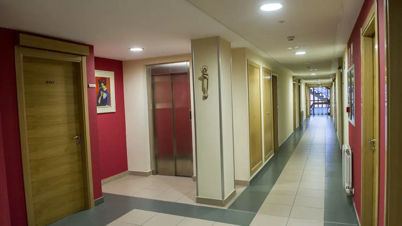 Pasillo de la residencia Laboure con puertas de madera, un ascensor y una pintura.