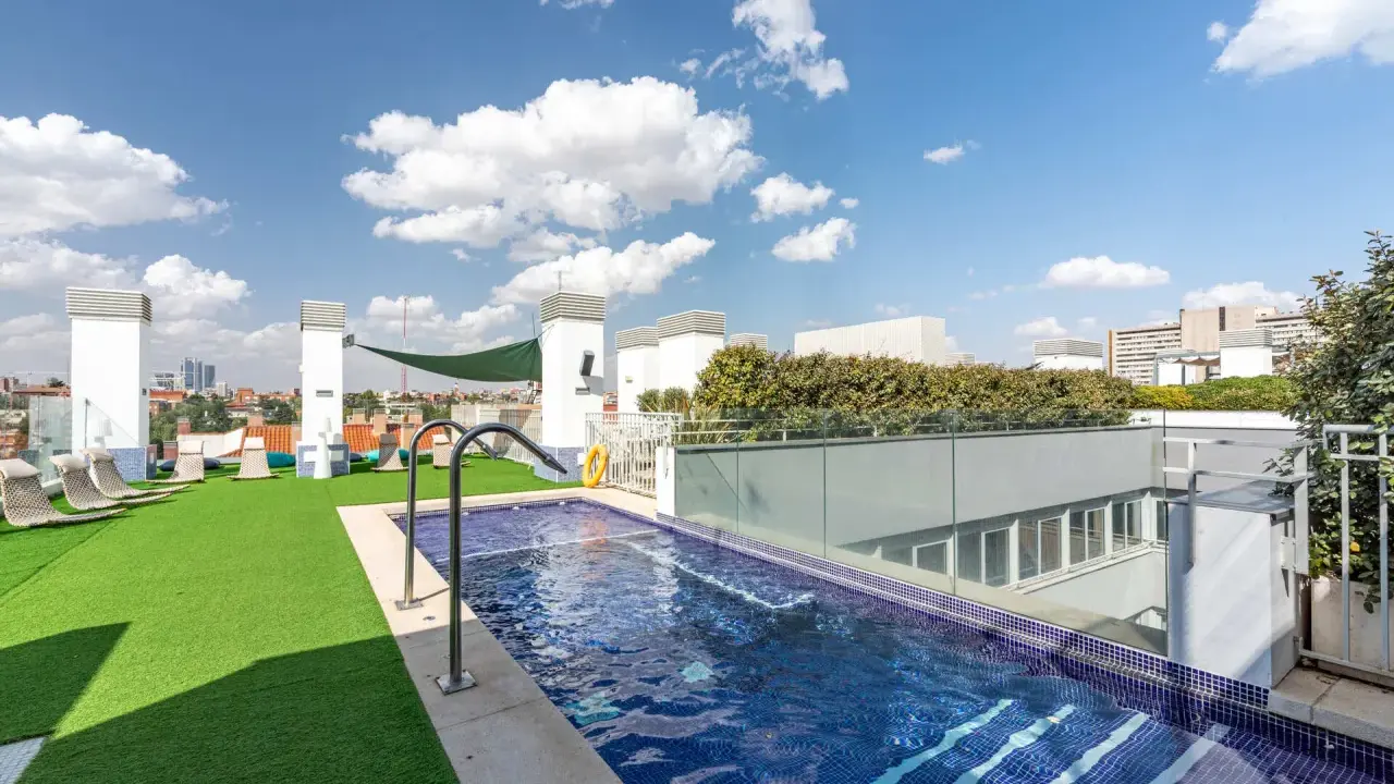 Resa Claudio Coello Madrid: piscina en azotea con césped artificial, tumbonas y vistas urbanas.