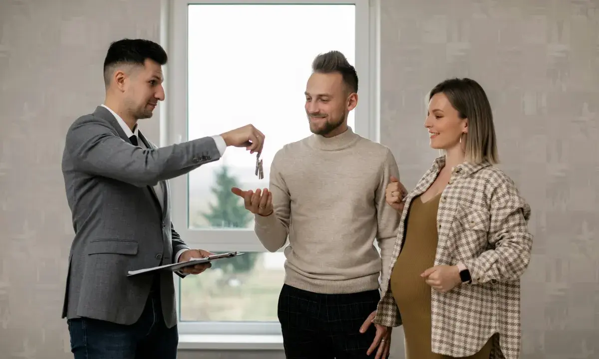 Agente inmobiliario entrega llaves a pareja embarazada. Un momento clave, como en la jurisprudencia sobre entrega de llaves.