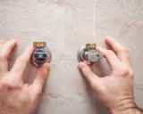 Manos ajustando la llave de paso de agua general, un componente esencial para el control del suministro.