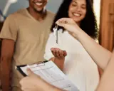 Pareja feliz recibe llaves de su nuevo hogar. Se discute la duración del contrato de alquiler.