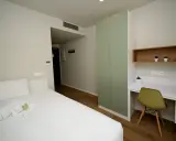 Habitación moderna con cama, armario verde y escritorio. Un espacio acogedor en Xior The Lofttown, listo para tu estancia.