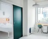 Habitación moderna con cama y escritorio. La puerta corredera verde es un detalle llamativo en este espacio, como un ecla noisy le grand.