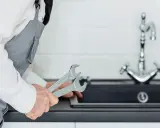 Fontanero con llaves inglesas, listo para reparar un grifo roto en un piso de alquiler. ¿Quién paga la reparación?