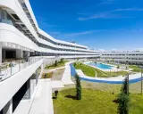 Modern residence in Madrid with curved white buildings, a pool, and green spaces.
