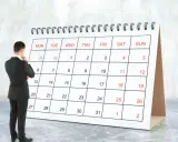 Hombre de traje frente a un calendario, pensando en el **artículo 9 de la LAU** y las fechas importantes.