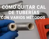 Mano enguantada muestra tubería con acumulación de cal. Llave inglesa naranja al fondo. Aprende cómo quitar cal de tuberías.