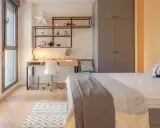 Habitación moderna en residencia San Bernardo Madrid. Escritorio, cama y armario gris. Ventanal con luz natural.