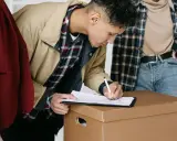 Jóvenes firmando un contrato de mudanza, quizás relacionado con la ley de arrendamientos urbanos.