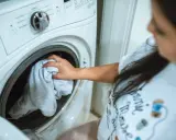 Mano saca ropa de lavadora. Espera que la lavadora haga mucho ruido al centrifugar.