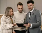 Pareja revisa documentos con un agente inmobiliario, discutiendo los términos de un subarriendo de vivienda.