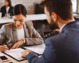 Mujer firma un precontrato de alquiler mientras un hombre revisa el documento.