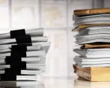 Dos pilas de documentos, una con clips negros y otra en sobres marrones, listas para ser enviadas como modelo de burofax para arrendatario.