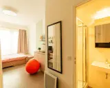 Estudio moderno en ecla villejuif con cama, zona de cocina, baño y un gran balón naranja.