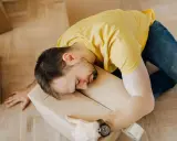 Hombre agotado durmiendo sobre una caja, quizás reflexionando sobre la diferencia entre comodato y precario tras una mudanza.