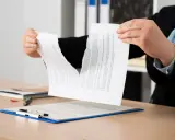 Manos rasgando un contrato, simbolizando la indemnización por incumplimiento de contrato de alquiler.