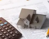 Casa modelo sobre formulario 1040, calculadora y lápiz. El arte 3 lau se relaciona con la planificación fiscal.