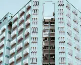 Edificio de apartamentos de color menta con filas de ventanas y persianas blancas. Un recordatorio de que se puede echar a un inquilino por necesitar el piso.