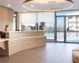 Recepción moderna y luminosa de living studios Alcobendas, con mostrador curvo, plantas y un sofá curvo.