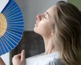 Mujer abanicándose para refrescarse, una solución para como ventilar una habitación sin ventana y combatir el calor.