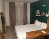 Habitación moderna en The Student Hotel Paris. Cama blanca, escritorio de madera y decoración "Let's Stay In".