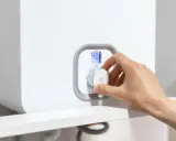 Mano ajustando el control de una caldera. La pantalla muestra 48°C. La presión caldera por debajo de 1 bar es una preocupación.