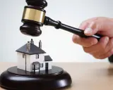 Martillo de juez golpea una casa en miniatura. ¡Qué mala suerte si estoy de alquiler y el piso sale a subasta!