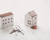 Maquetas de casas y llaves sobre gráficos financieros. El arte 17 lau sugiere una inversión inmobiliaria.