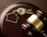 Martillo de juez y llaves con llavero de casa, simbolizando el lanzamiento de desahucio a terceros ocupantes.