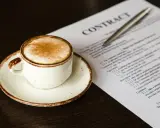 Taza de café con canela junto a un contrato, quizás revisando el artículo 27 de la LAU.