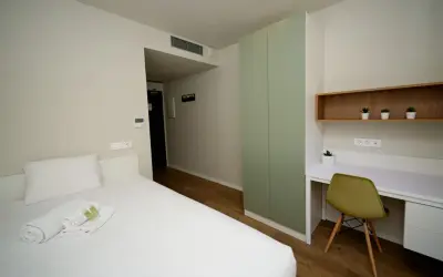 Habitación moderna con cama, armario verde y escritorio. Un espacio acogedor en Xior The Lofttown, listo para tu estancia.