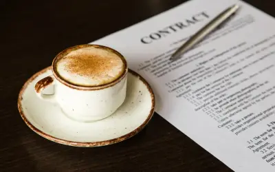 Taza de café con canela junto a un contrato, quizás revisando el artículo 27 de la LAU.