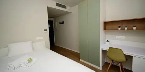 Habitación moderna con cama, armario verde y escritorio. Un espacio acogedor en Xior The Lofttown, listo para tu estancia.