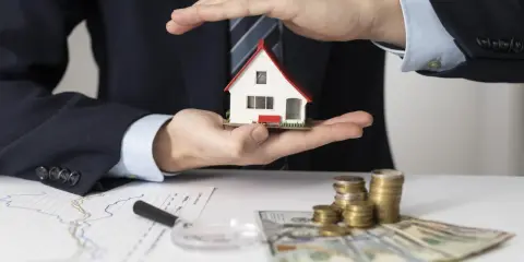 Man in suit holds a miniature house, symbolizing a **contrato de arras alquiler**. Stacks of coins and banknotes suggest financial aspects of the deal.