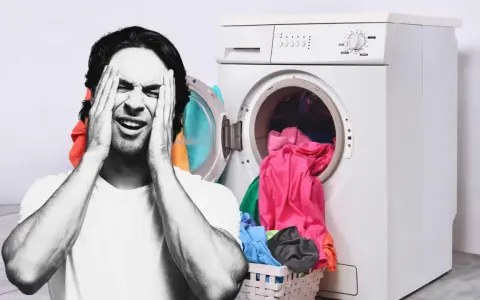 Hombre frustrado con las manos en la cara junto a una lavadora llena de ropa. ¿Por qué mi lavadora no centrifuga?