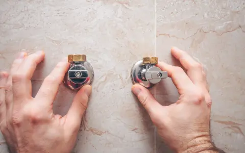 Manos ajustando la llave de paso de agua general, un componente esencial para el control del suministro.