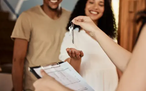 Pareja feliz recibe llaves de su nuevo hogar. Se discute la duración del contrato de alquiler.