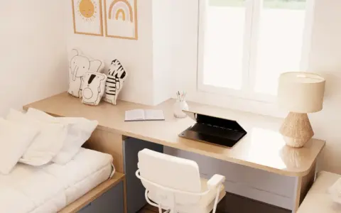 Un escritorio de madera con un portátil, libro y lámpara, junto a una cama y cojines de animales. Este es un ejemplo de cómo un **loft que es** funcional y acogedor.